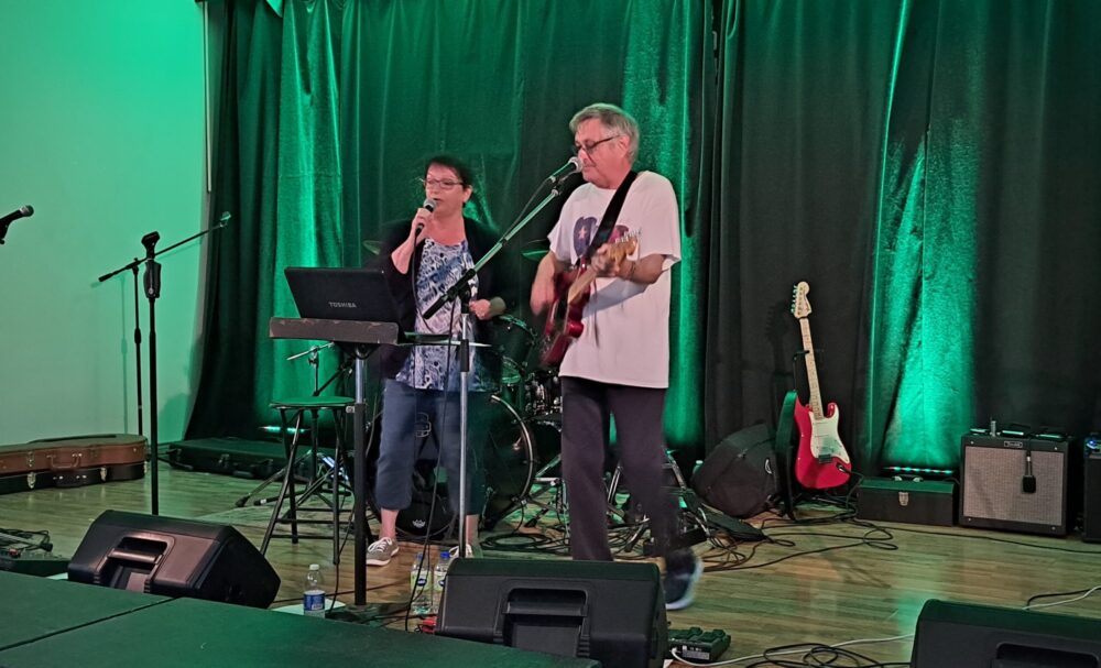 Un guitariste et une chanteuse en performance durant un concert.