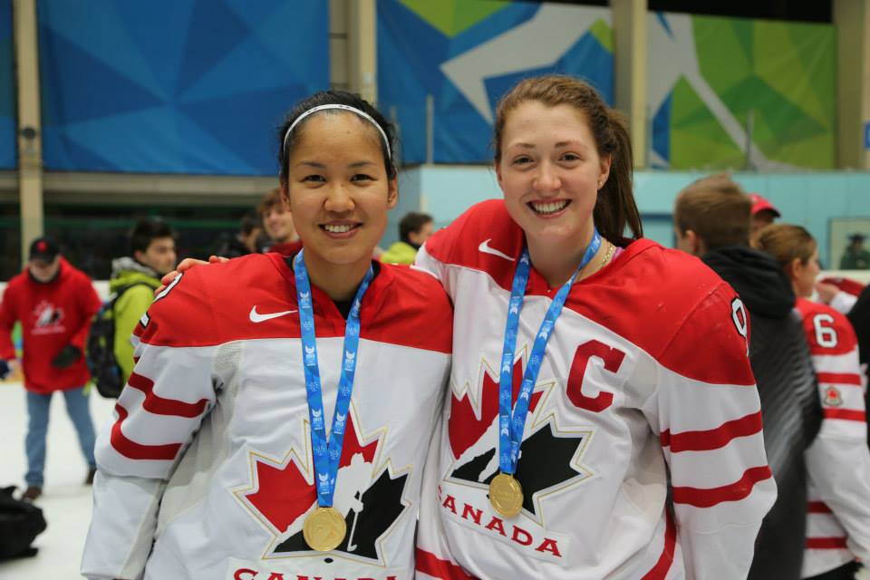 Deux femmes portant l'uniforme de l'équipe du Canada au hockey, affichant fièrement leur médaille