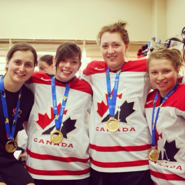 Quatre joueuses de hockey portant fièrement chacune leur médaille d'or dans l'uniforme du Canada.
