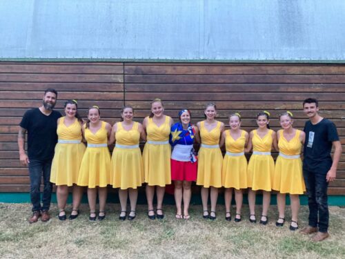 Des jeunes filles portant des robes jaunes avec deux hommes habillés en noir.