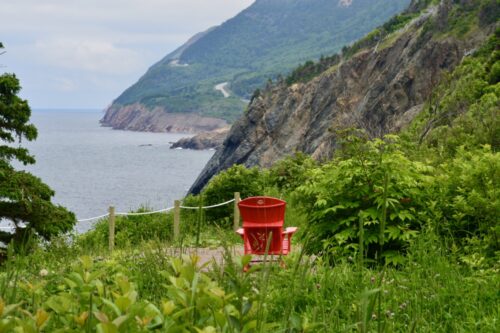 Une chaise rouge sur la falaise, là où la mer rencontre les montagnes.