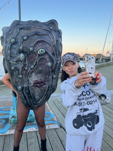 Photo of Pearl the oyster mascot posing for a selfie with a woman.