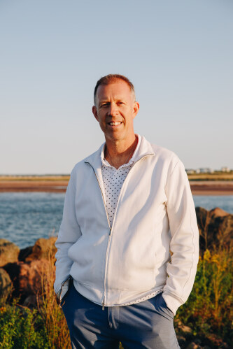 Portrait photo of Ride Solar co-owner Steve Arnold standing in front of a beach.