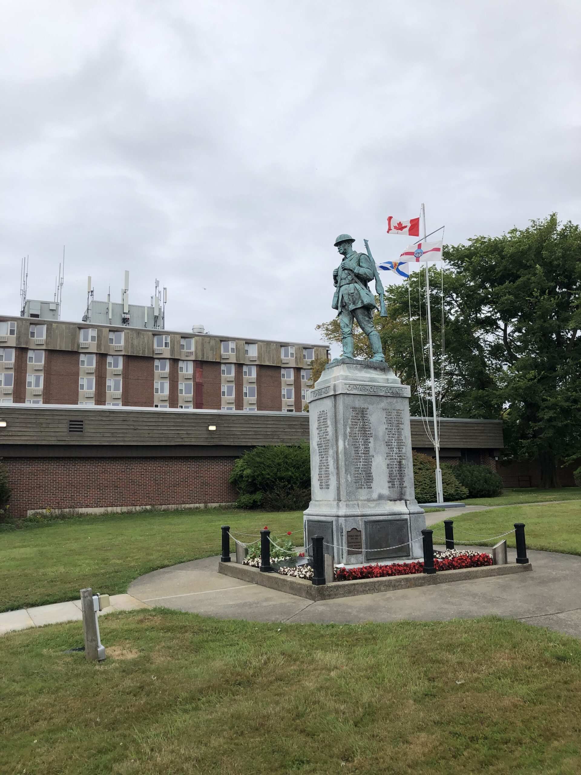 Au centre d'un parc gazonné, une statue en bronze de 7 pieds de hauts d’un soldat qui marche avec un sac à dos et un fusil. Le cénotaphe, qui est posé sur une base de béton, est entouré par un trottoir avec 3 voies qui en ressort. Celle qu’on voit se rend vers un mât de drapeau portant les drapeaux du Canada, de la Nouvelle-Écosse, et un drapeau d’ancien combattant. En arrière-plan, un mur de brique rouge, ou devant, on voit un espace entre deux arbustes où le comité propose de déposer le monument.