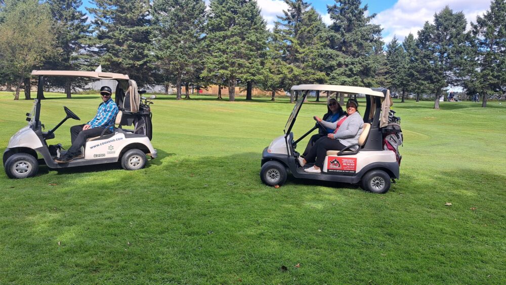 Trois personnes pour deux voiturettes de golf tout sourire lors d'une journée ensoleillée