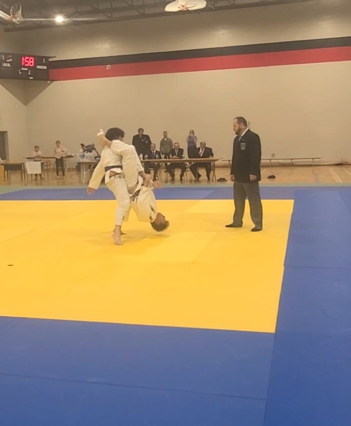 Combat de judo, un judoka tient son adversaire dans les airs la tête à l'envers