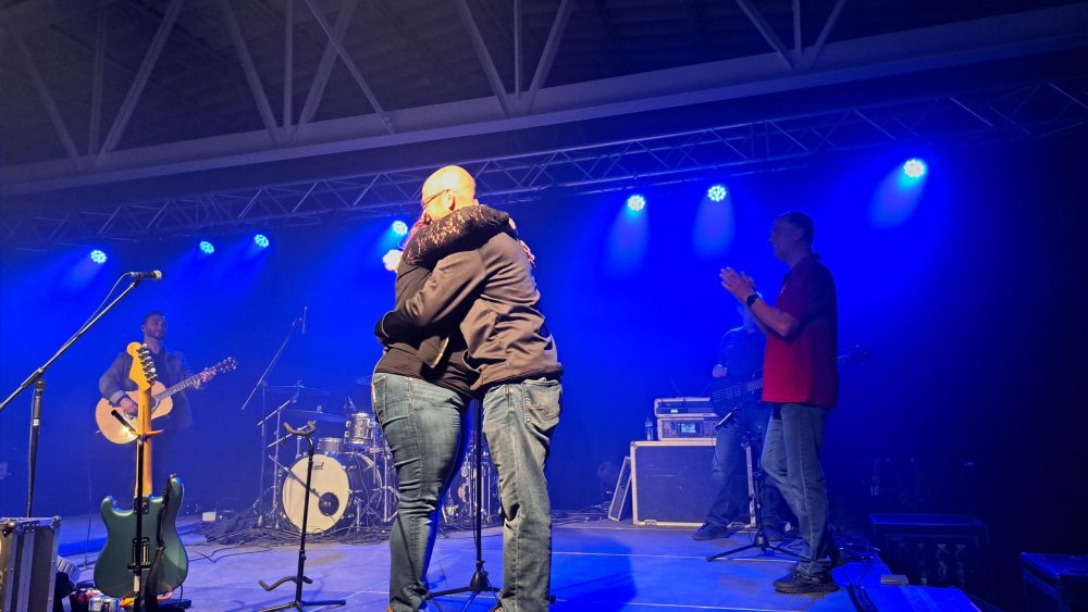 Un couple se donne un câlin sur une scène lors d'un concert