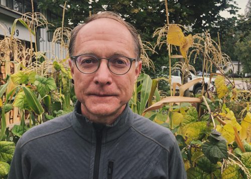 A man stands before some corn.