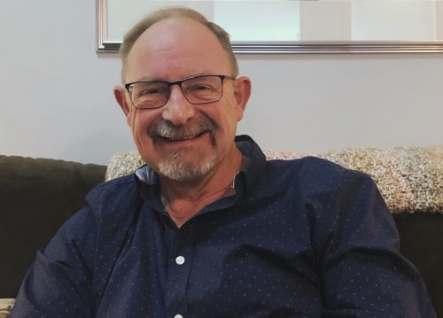 A man sits on a couch and smiles.