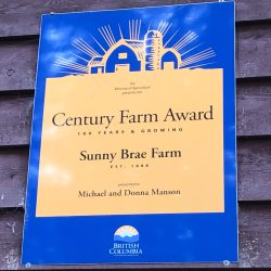 A sign featuring a graphic of a farm and black letters on a beige background displays a government heritage award.