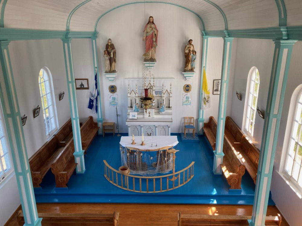 Le choeur d'une petite chapelle peinte en blanc et turquoise.