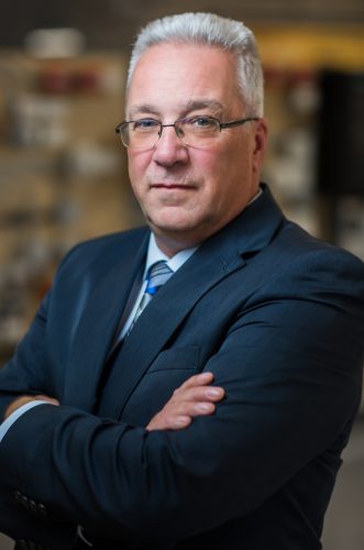 Portrait photo of Brad Smith,executive director of the Mainland Nova Scotia Building Trades Council. He is wearing glasses and a suit and is seen crossing his arms.