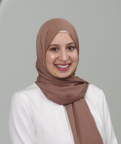 A professional photo of a woman smiling in front of a white background, she is the program director of the first non-profit catering to muslim women and children in Atlantic Canada.