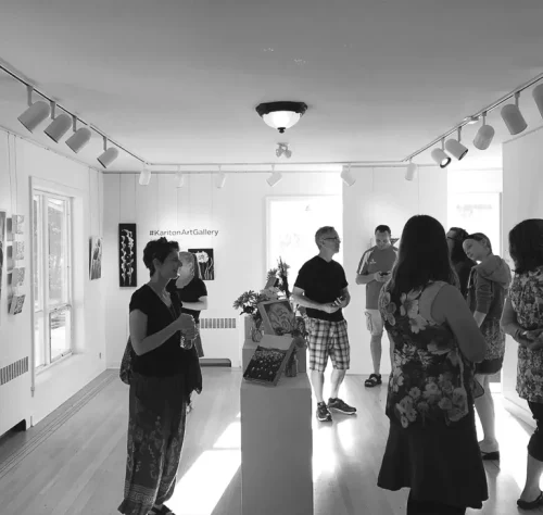 A black and white photo of inside the Kariton art gallery while patrons look at the art.