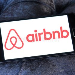 A cell phone depicts a white screen with red letters that say "airbnb."