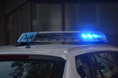 A stock photo of blue police sirens on top of a car against a gray background