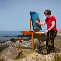 Une dame en train de créer une peinture au bord de la mer.