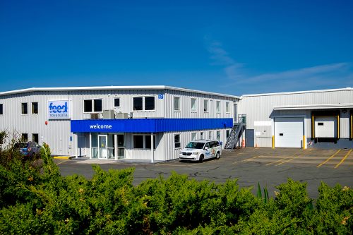 The white and blue exterior of Feed Nova Scotia's charity located in Dartmouth. There is a blue sky in the background.