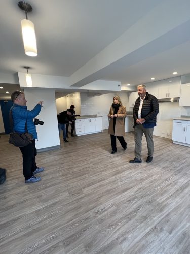 Photo of Minister John Lohr withNorth End Community Health Centre CEO Marie-France LeBlanc touring the transformed housing space in Dartmouth. They are standing in a living room. 