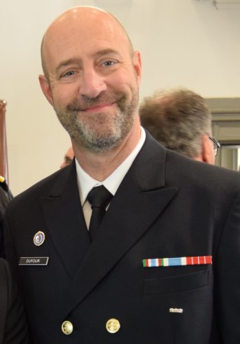 Un homme en costume de la Garde côtière canadienne sourit à la caméra.