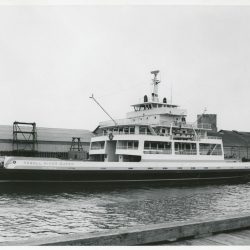 A black and white image depicts a new ferry boat shortly after being launched.