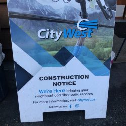 A blue, green and white sandwich board announces construction.