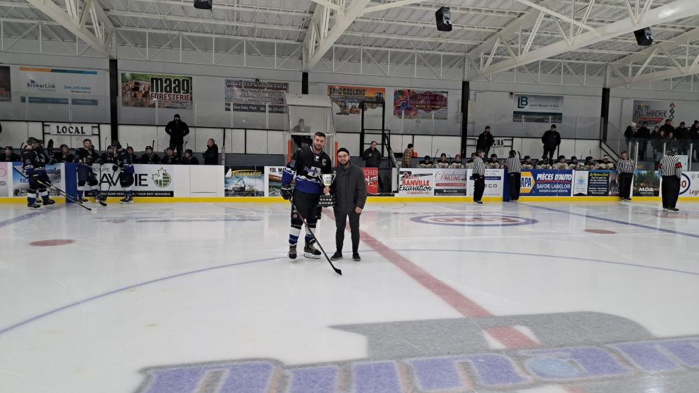 Le président du Circuit Régional de Hockey, Alexis Ouellet, remet le trophée de l'équipe championne de la saison régulière au capitaine du Dynamo de Kedgwick.