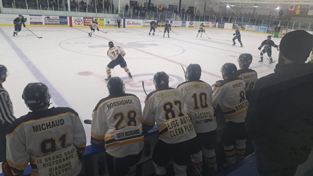 Partie de hockey vue derrière le banc des joueurs.