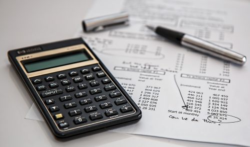 On vois une calculatrice, posée sur une feuille ou apparaissent des chiffres de comptabilité.