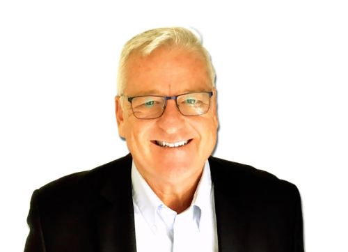 A professional head shot of Don Joyce. He is standing against a white background wearing a black suit, white dress shirt, and glasses.