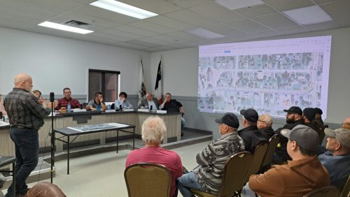 Un homme donne une conférence devant un groupe de citoyens, dans une salle de conseil municipal