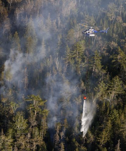 Un hélicoptère relâche sa cargaison d'eau sur un feu de forêt.