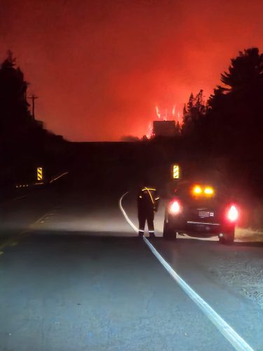 Une personne et une voiture en face des feux de forêt.