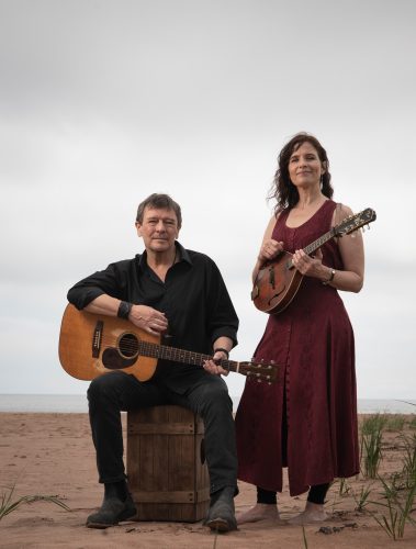 Un homme et une femme avec des instruments de musique au bord de la plage.