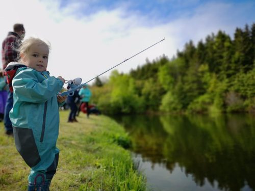 Une petite fille à la pêche dans un lac.