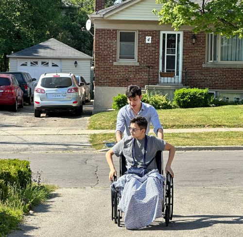 Josue llegando a su casa después de su cirugía ,en su silla de ruedas siendo ayudado por uno de sus amigos. 