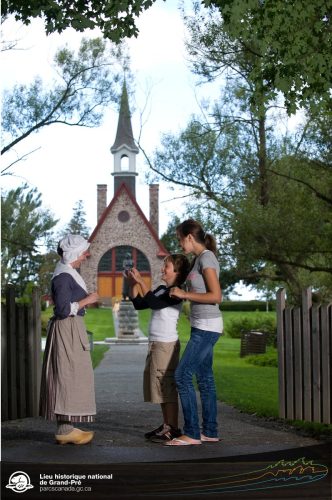 Deux personnes parlant à une interprète costumée en avant d'une église.