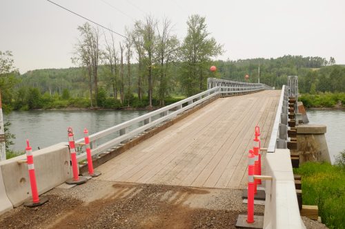 A view of a bridge with pylons at the entrance. The bridge covers the Bulkley River in the community of Quick, 30 kms west of Smithers on Highway 16.