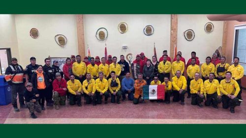 Un grupo de bomberos mexicanos en Fort Albany, junto con la bandera de México. 