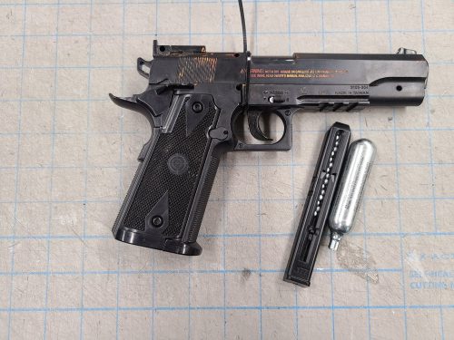 Photo of a black airsoft replica firearm with magazine and air canister