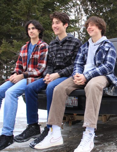 Trois jeunes garçons assis à l'extérieur.