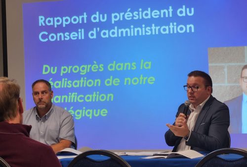 Michel Coté et Philippe Richard derriere la table de l'AGA de l'ARCf, en arriere une projection de PowerPoint