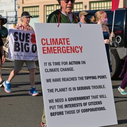 Man holds a sign reading Climate emergency