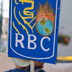 Man holds a sign with the logo of the RBC with a globe. on fire