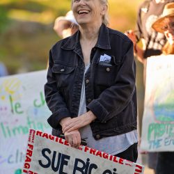 Woman holds a sign reading sue big oil
