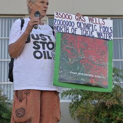 Woman holds a sign showing map of fracked gas wells in British Columbia.