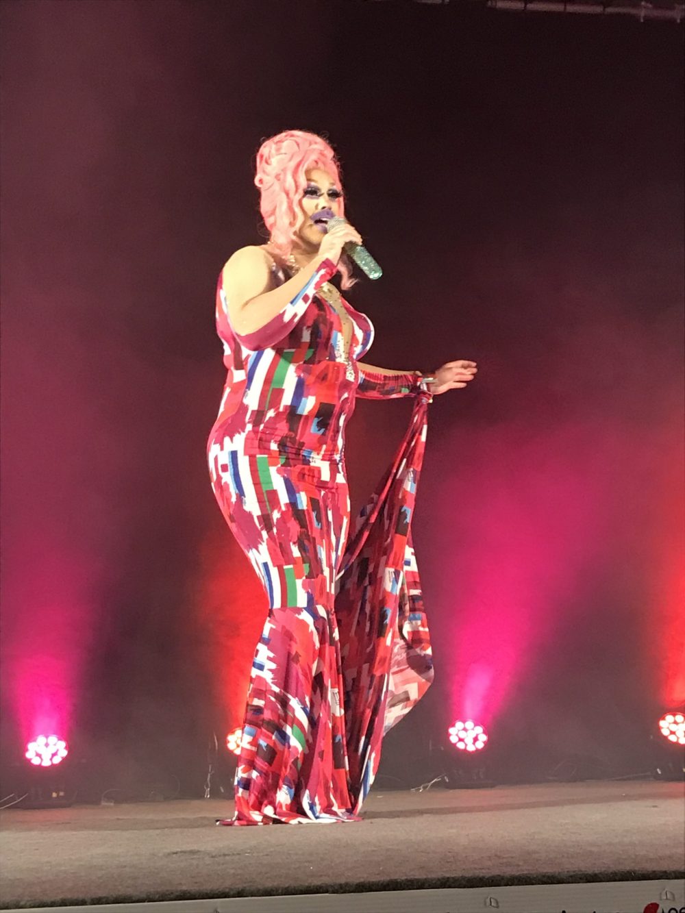 Une drag costumée d'une robe et perruque rouge