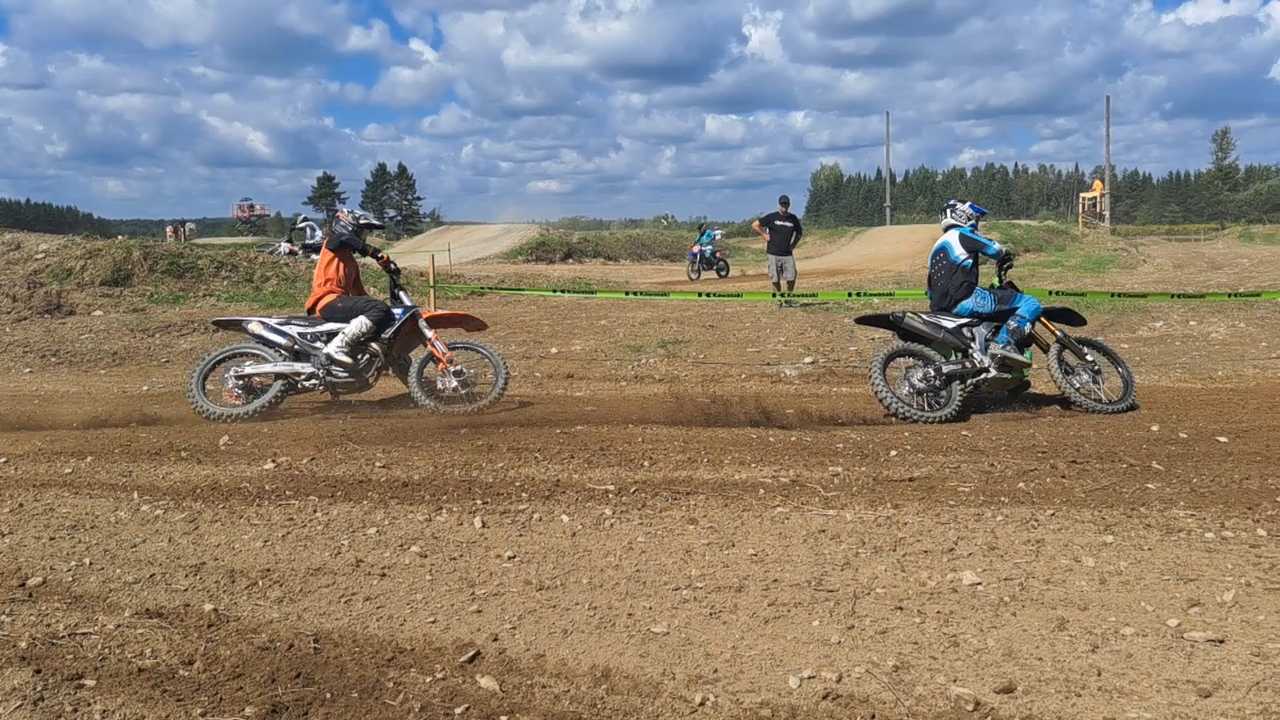 Deux pilotes de motocross en action sur la piste prenant un virage à gauche, lors d'une journée ensoleillée