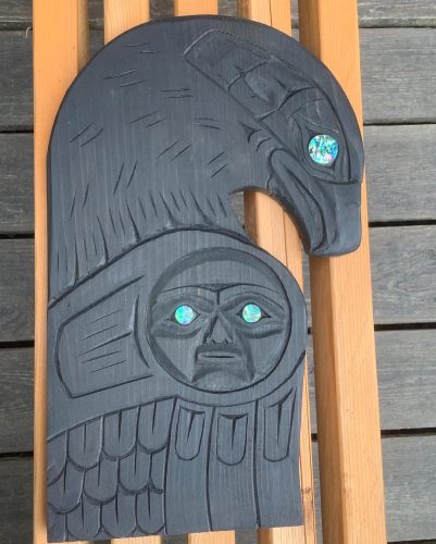 A carving of a black Raven with an abalone for an eye.