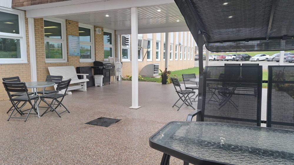 Vue sur une terrasse au plancher d'époxy composé de quelques tables et chaises foncées.